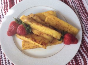 Fried pinapple slices on a plate with strawberries.