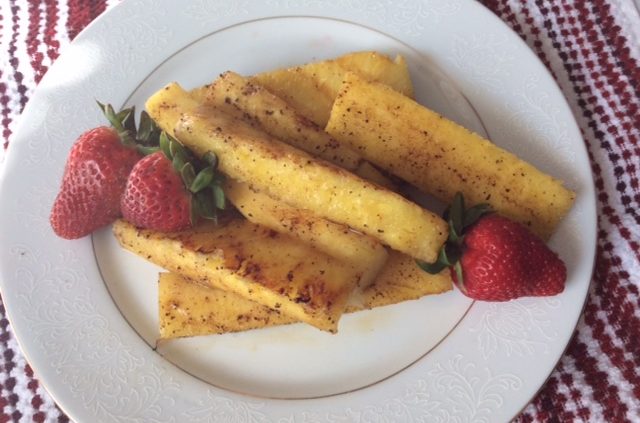 Fried pinapple slices on a plate with strawberries.